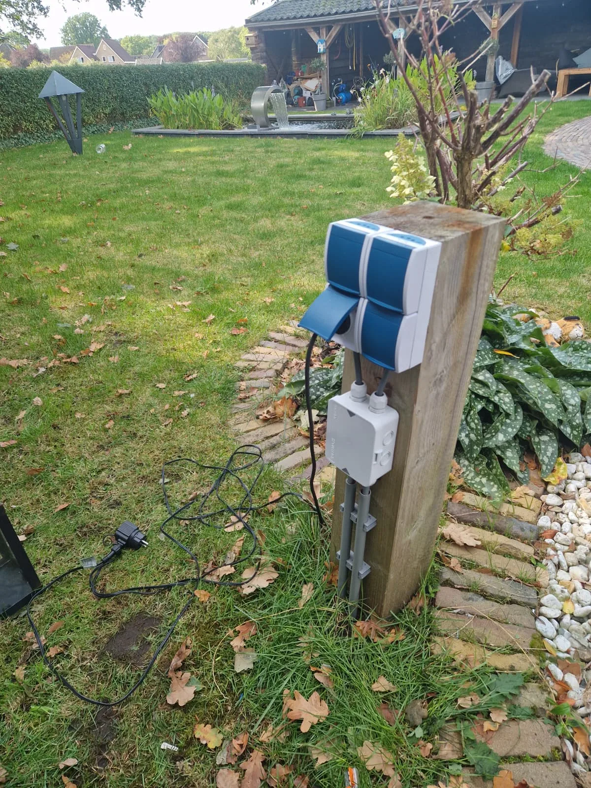Buitenwandcontactdozen op een paal in de tuin in Erm